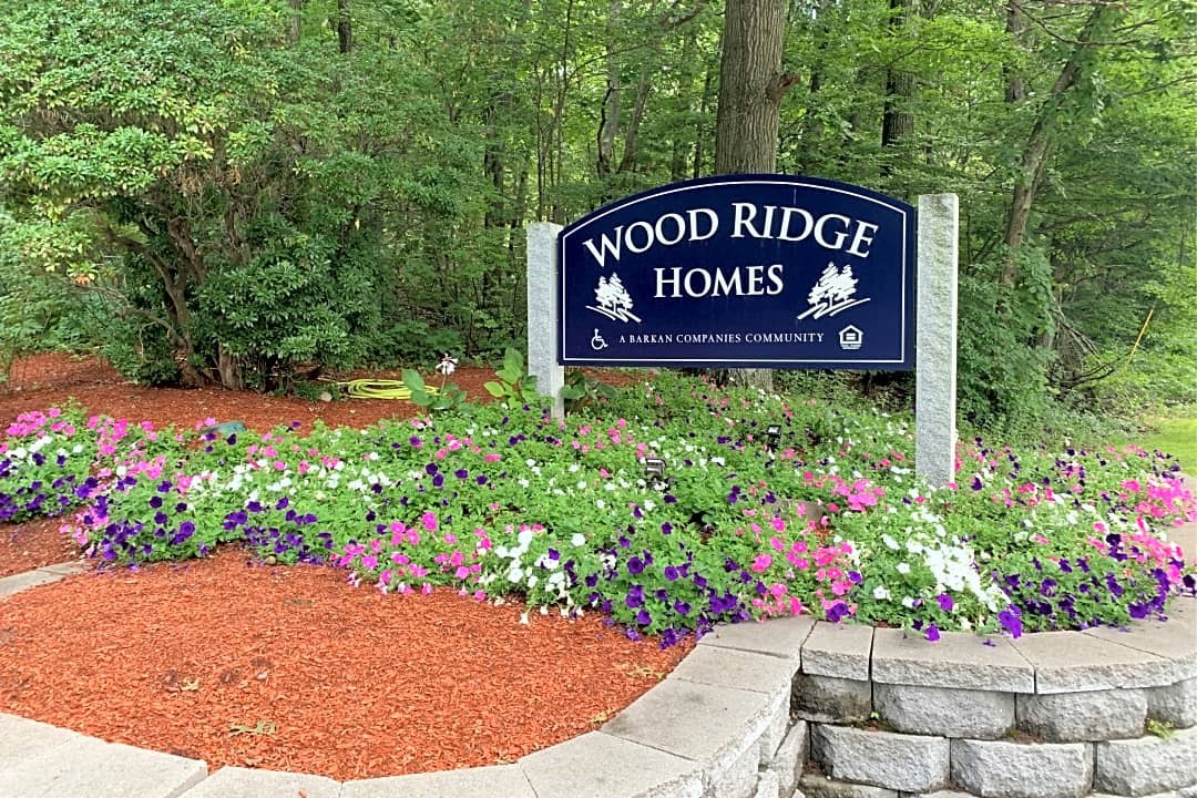 sign for wood ridge homes in front of flowers